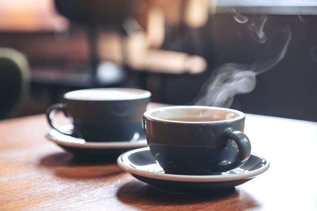 Closeup image of two blue cups of hot latte coffee
